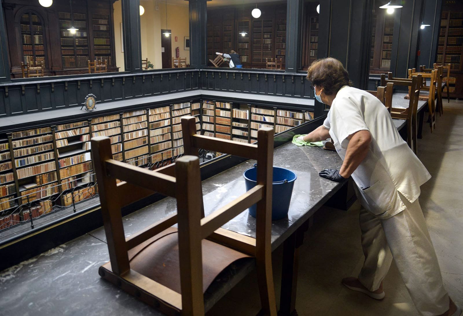 Persona limpiando mesa en biblioteca antigua