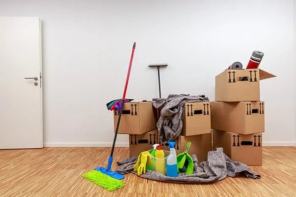 Caja de mudanza con productos de limpieza y trapeador.