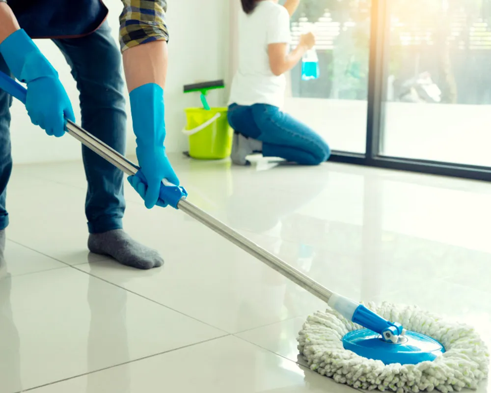 Personas limpiando suelos y ventanas de casa.